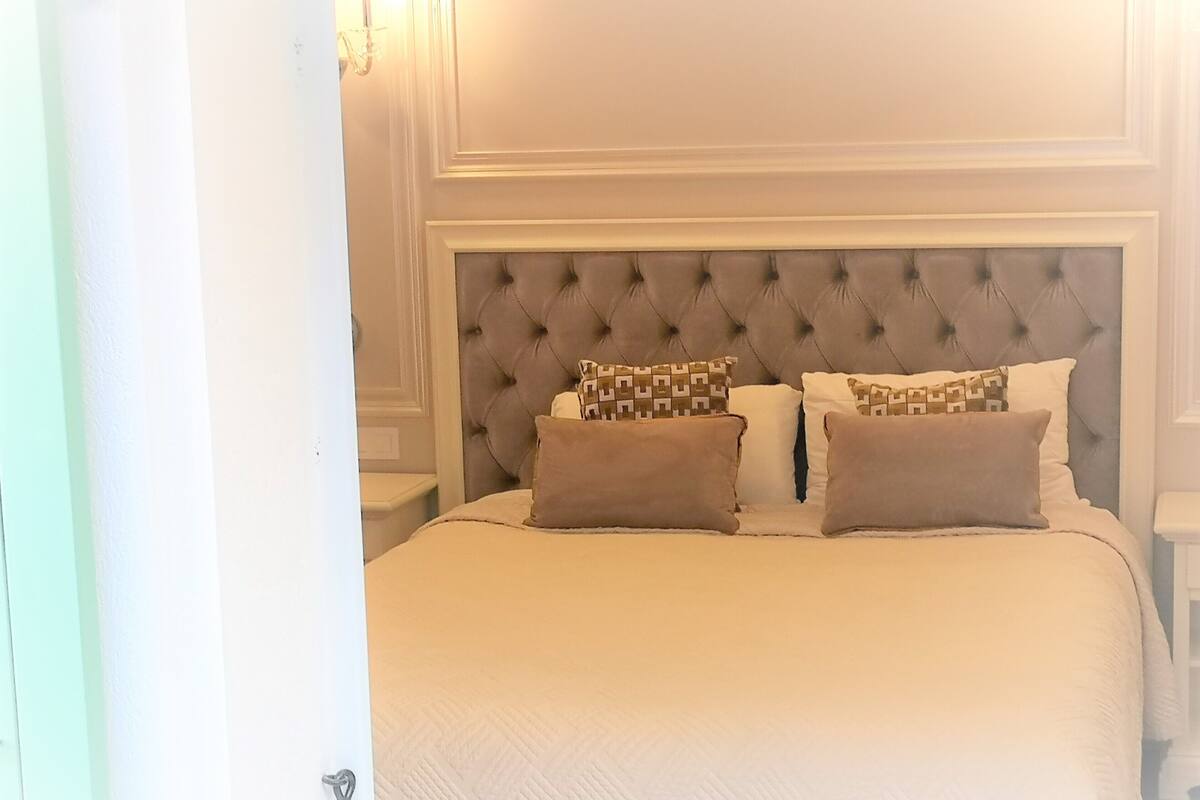 Una cama bien tendida con cabecera capitonada y almohadas estampadas.