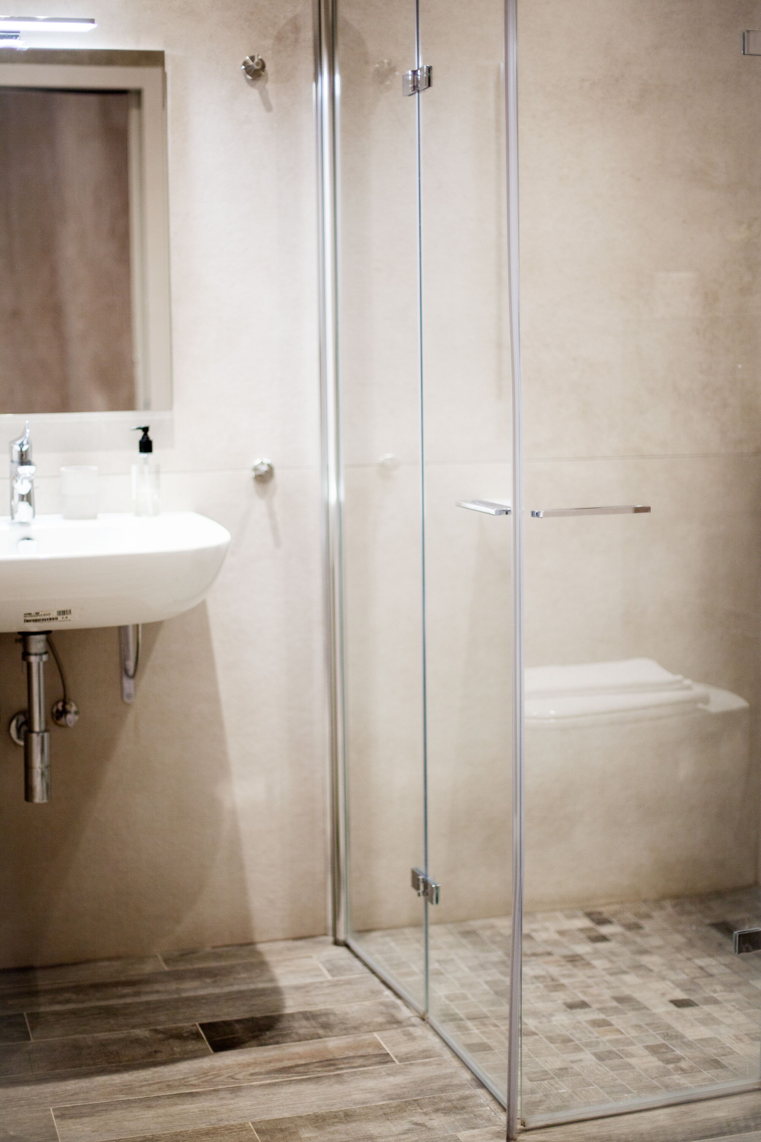 A bathroom with a glass shower enclosure, a sink, and a toilet.