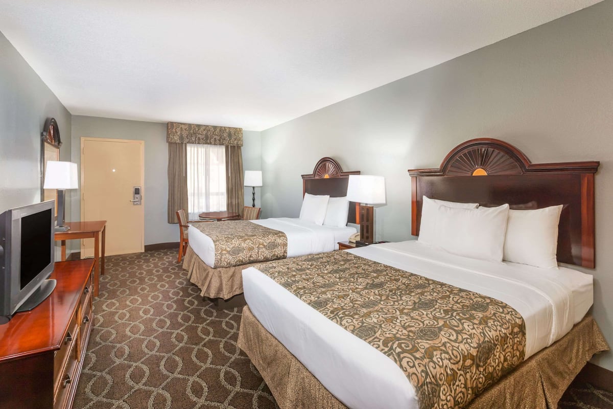 A hotel room with two beds, a TV, a desk, and a chair.