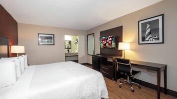 A hotel room with a bed, desk, chair, and a television.
