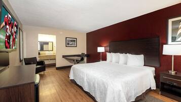 Une chambre d’hôtel avec un grand lit, un bureau, une chaise, une lampe de bureau et un tableau encadré au mur.