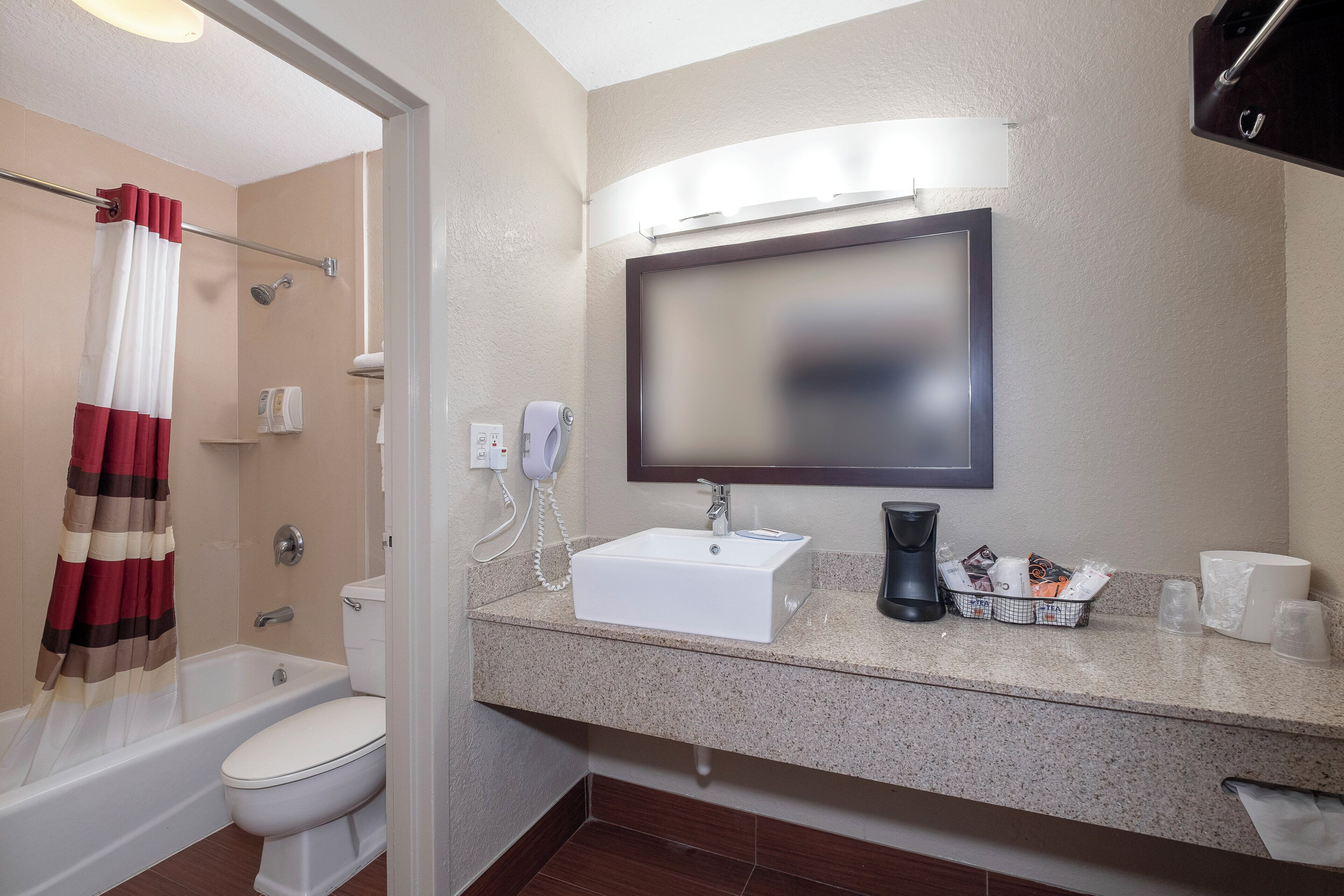 A bathroom with a toilet, shower, sink, and a mirror.