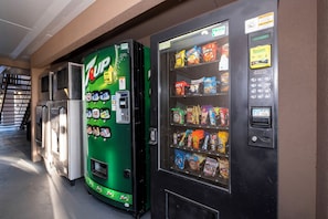 Un distributeur automatique de 7UP et un autre distributeur automatique proposant divers en-cas et boissons.