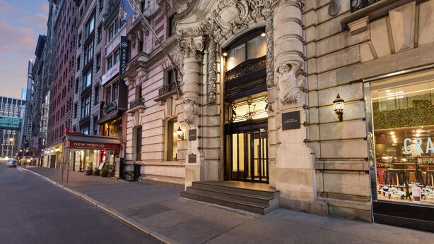 A historic building with ornate architectural details, a prominent entrance, and a visible storefront with a sign. - The Hotel @ Fifth Avenue (New York)
