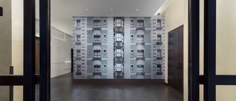 A hallway with a patterned wall and a modern elevator.