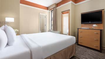 A hotel room with a large bed, a dresser, a flat-screen TV, and a window with curtains.