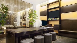 A modern kitchen with a central island, bar stools, a flat-screen TV, and a large window with a view of the city. - The Hotel @ Fifth Avenue (New York)