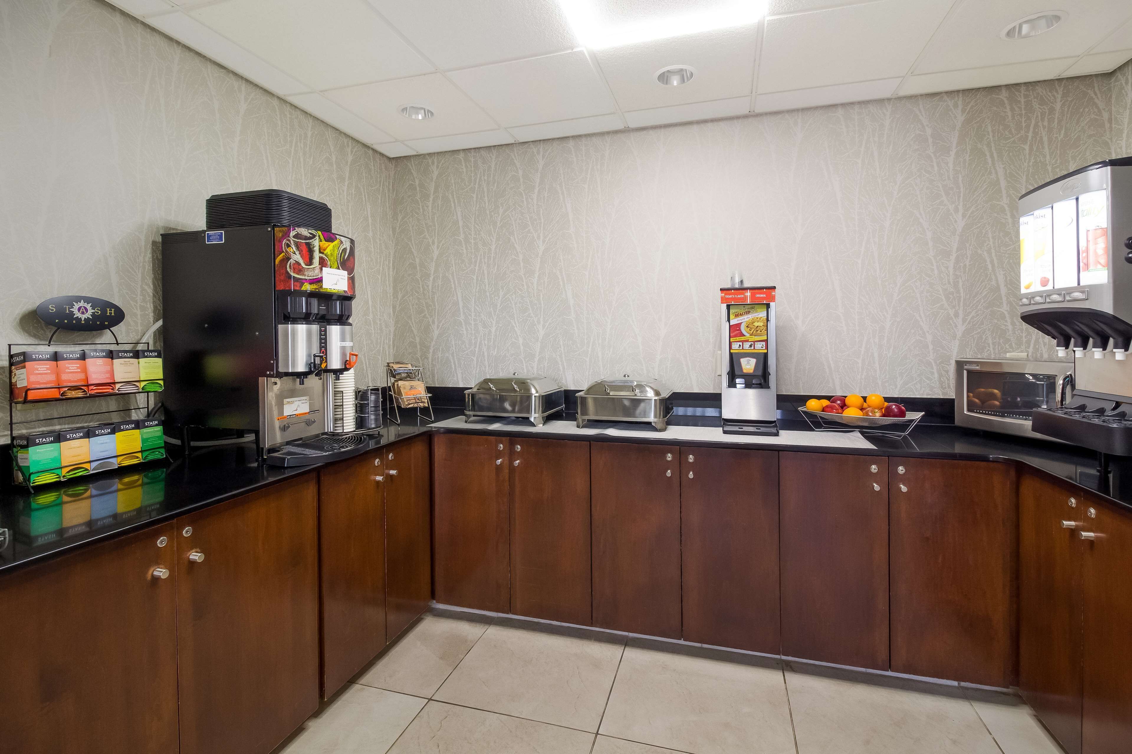 A self-service coffee station with multiple coffee machines, a fruit display, and a vending machine.