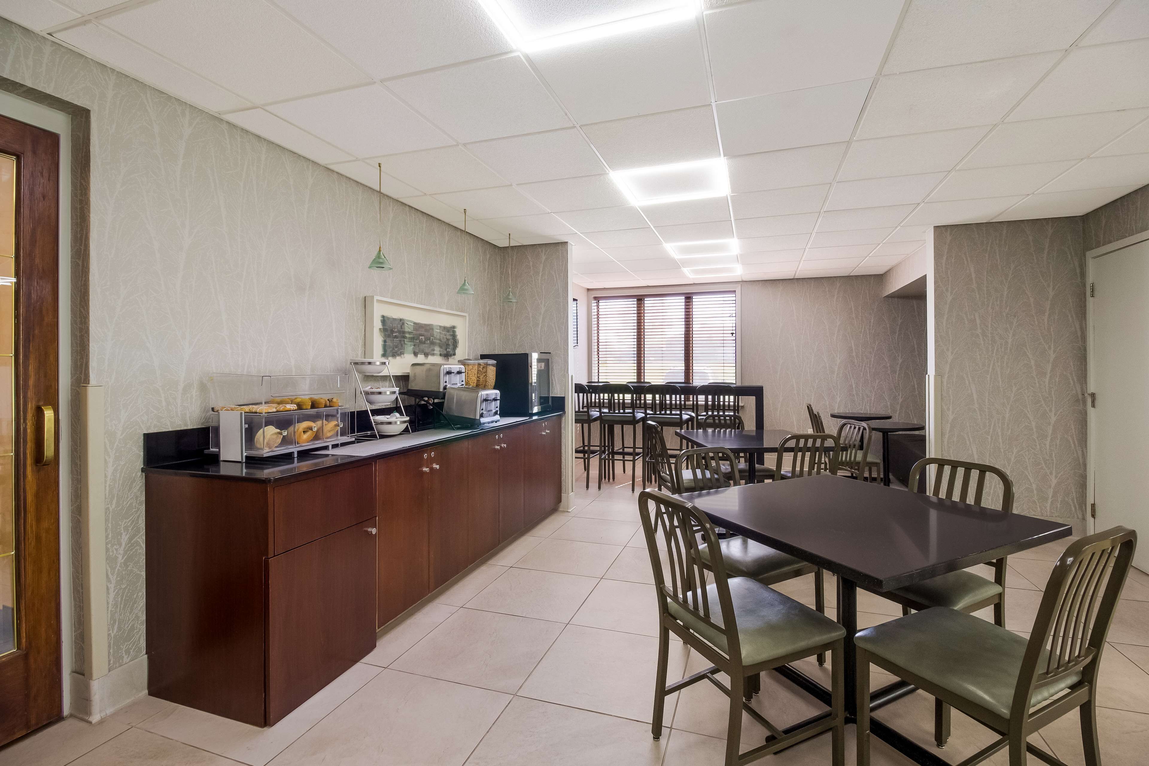 A dining area with a central table and chairs, a kitchenette with appliances, and a patterned wall.