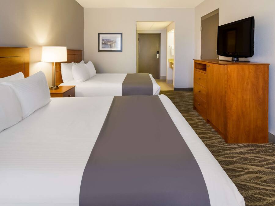 A hotel room with two beds, a TV on a wooden cabinet, and a framed picture on the wall.