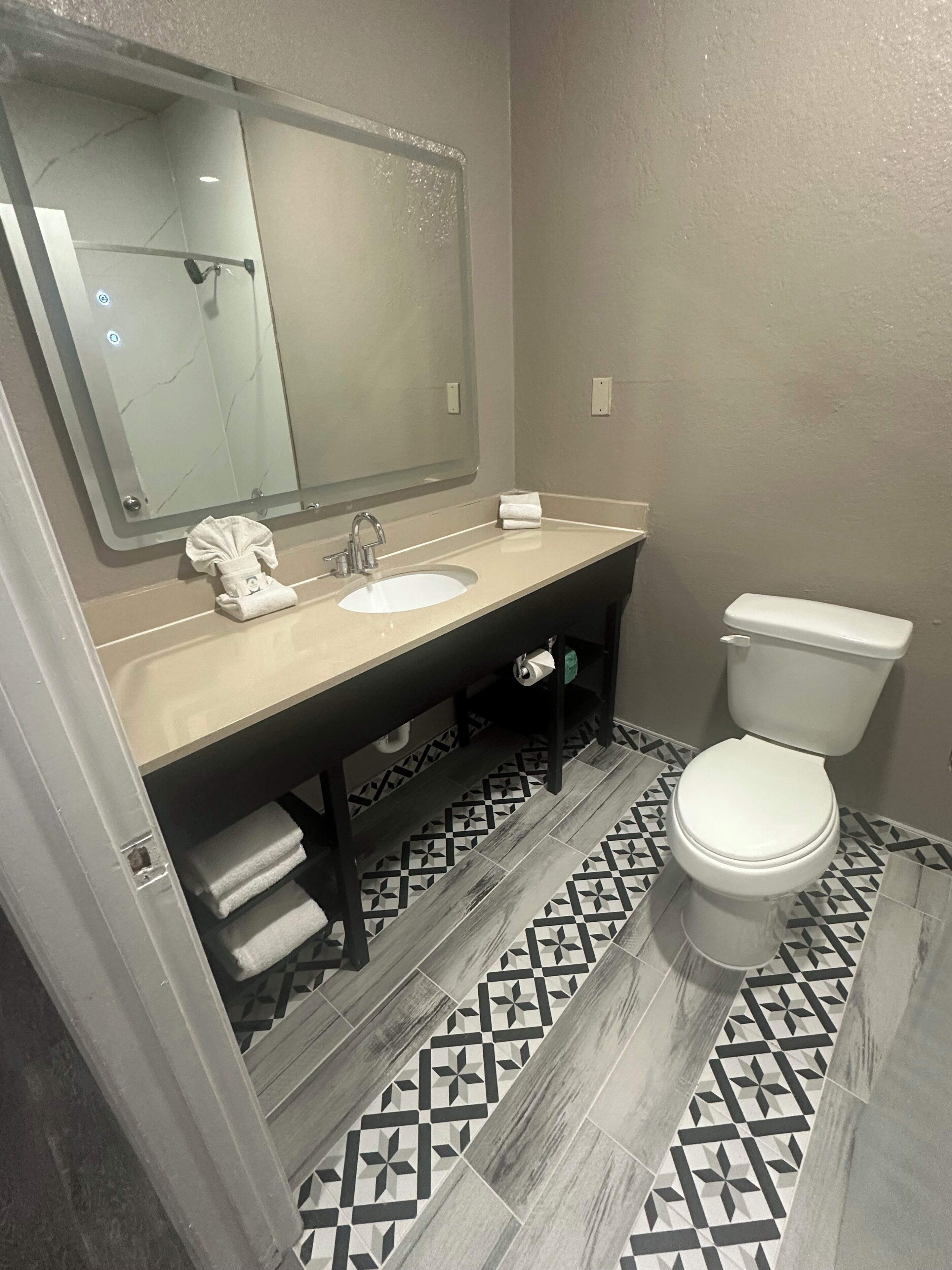 A bathroom with a sink, mirror, and toilet.