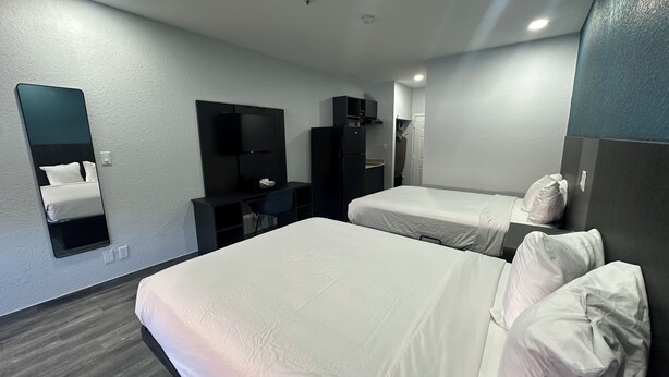 A hotel room with two beds, a desk, a mirror, and a wardrobe.