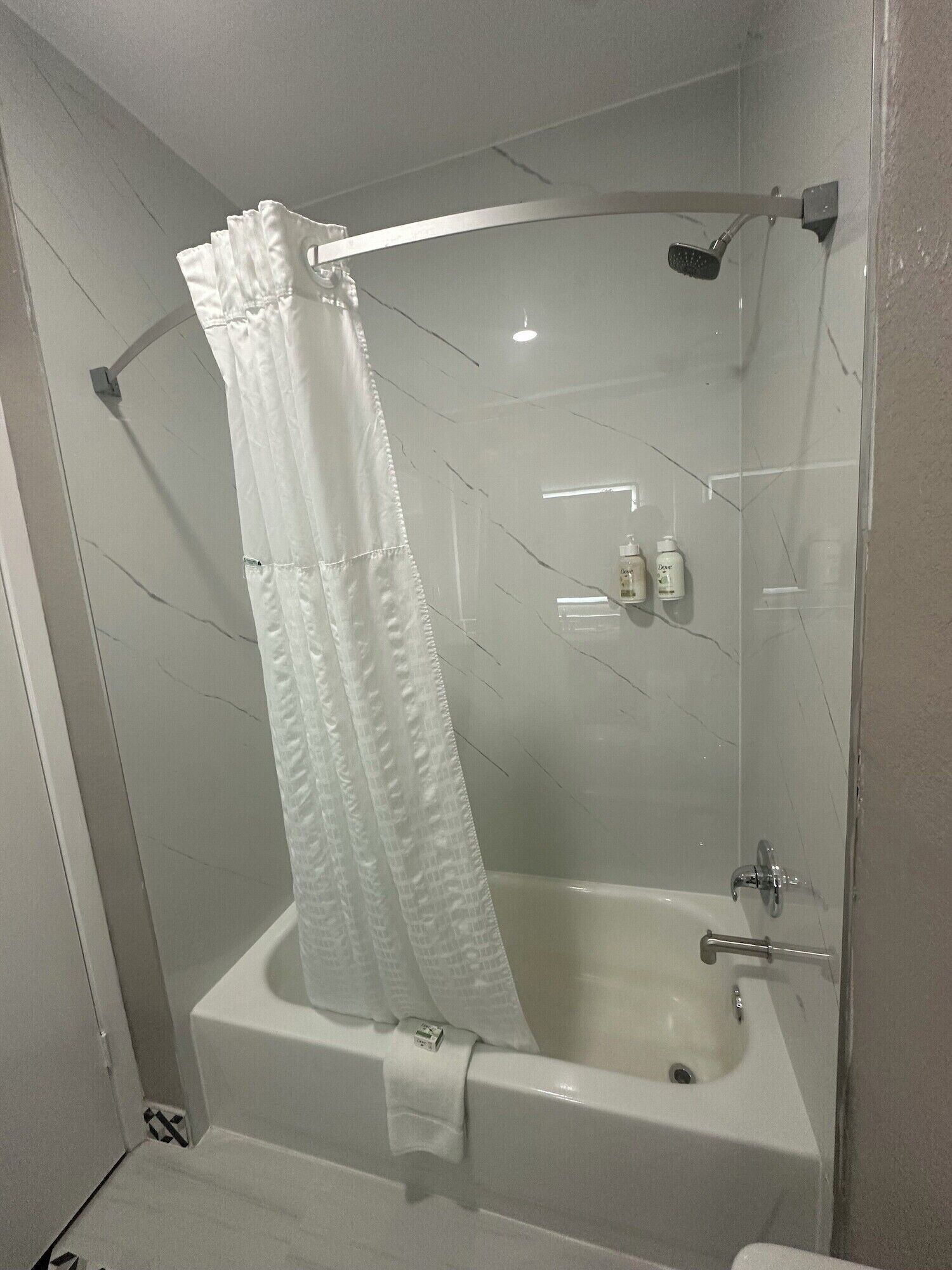 Une salle de bain équipée d’une baignoire, d’une douche et d’un espace de douche séparé par des parois en verre.