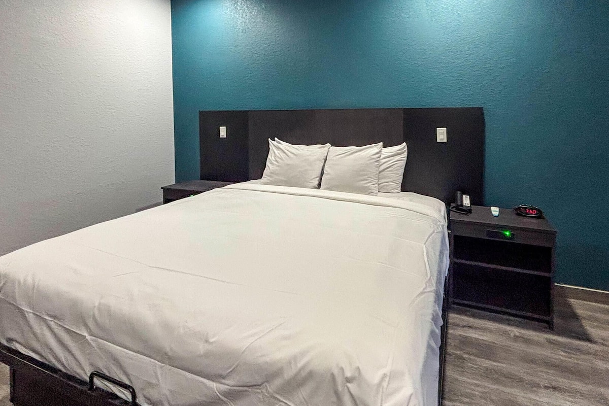 A neatly made bed with white bedding in a room with teal walls and a dark headboard.