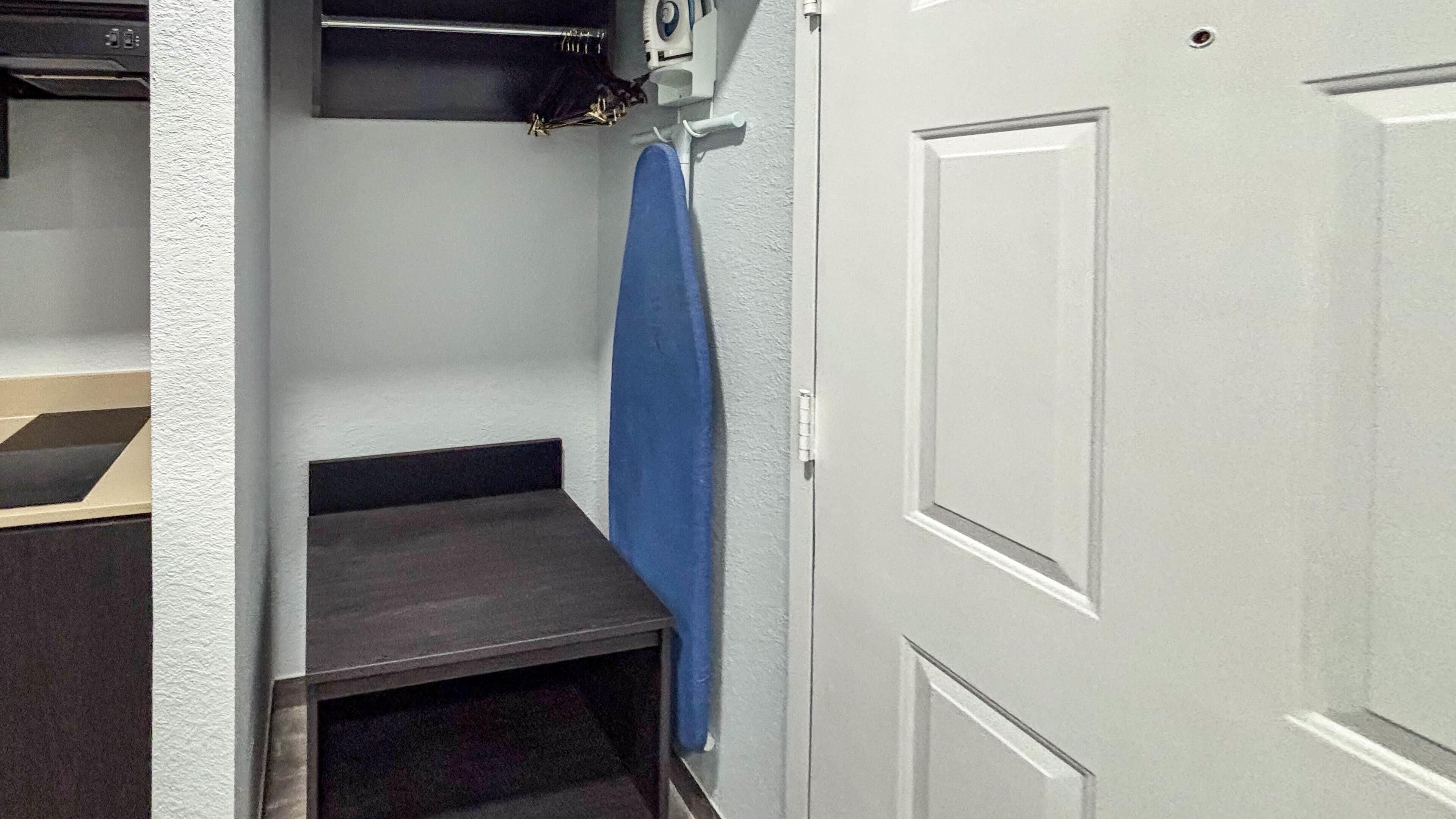 A narrow hallway with a door on the right and a small step leading to a dark-colored room.