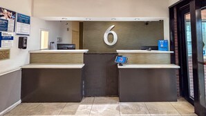 A reception area with a large number '6' sign, a reception desk, a digital kiosk, and a door with a keypad.
