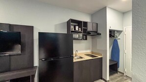 A compact kitchenette with a black refrigerator, microwave, and built-in oven.