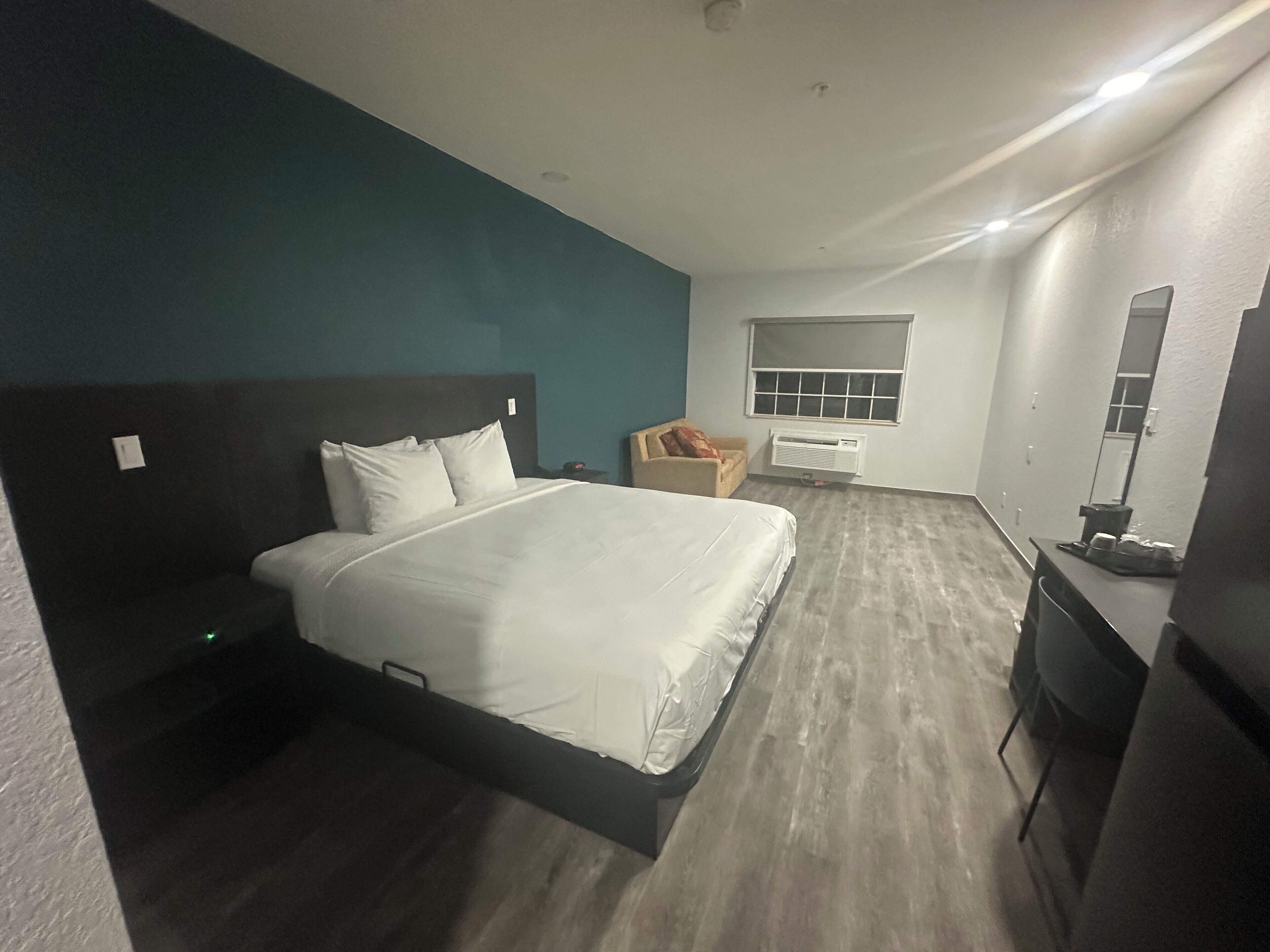 Una habitación de hotel con una cama, una silla, un escritorio y una ventana.