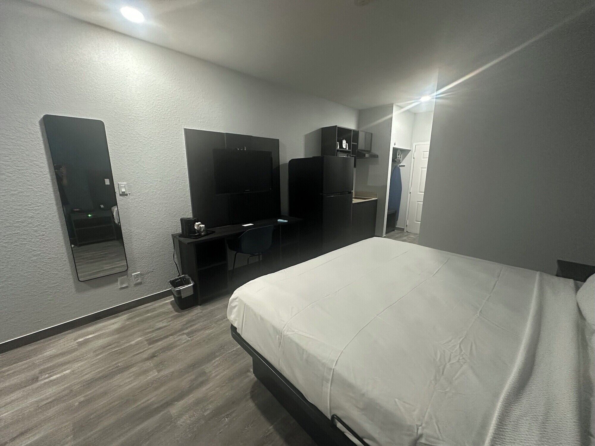Habitación de hotel con cama, escritorio con computadora, televisor, armario y espejo.
