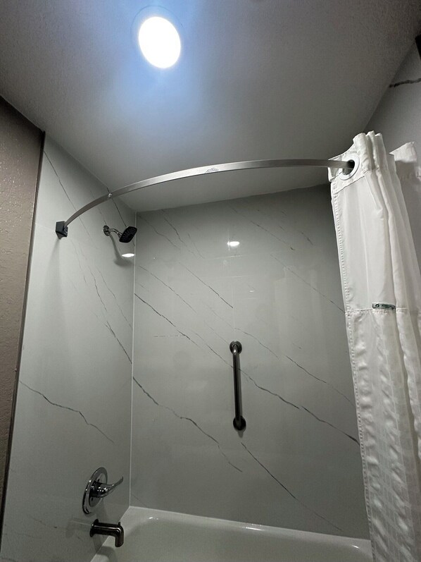 Een moderne badkamer met een douche, een badkuip en een toilet.