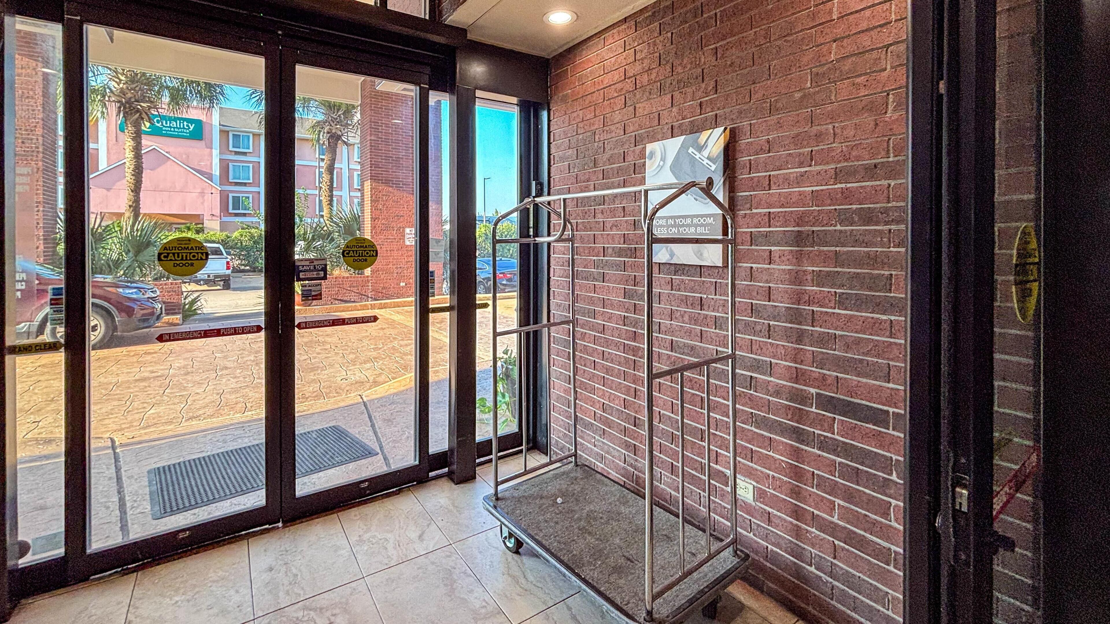 A hotel entrance with automatic doors, a metal barrier, and a sign indicating a 10% discount.