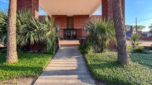 A pathway leading to a building with a brick facade and a covered entrance.