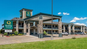 A hotel with a green and beige exterior, multiple floors, and a prominent 'Quality' sign.