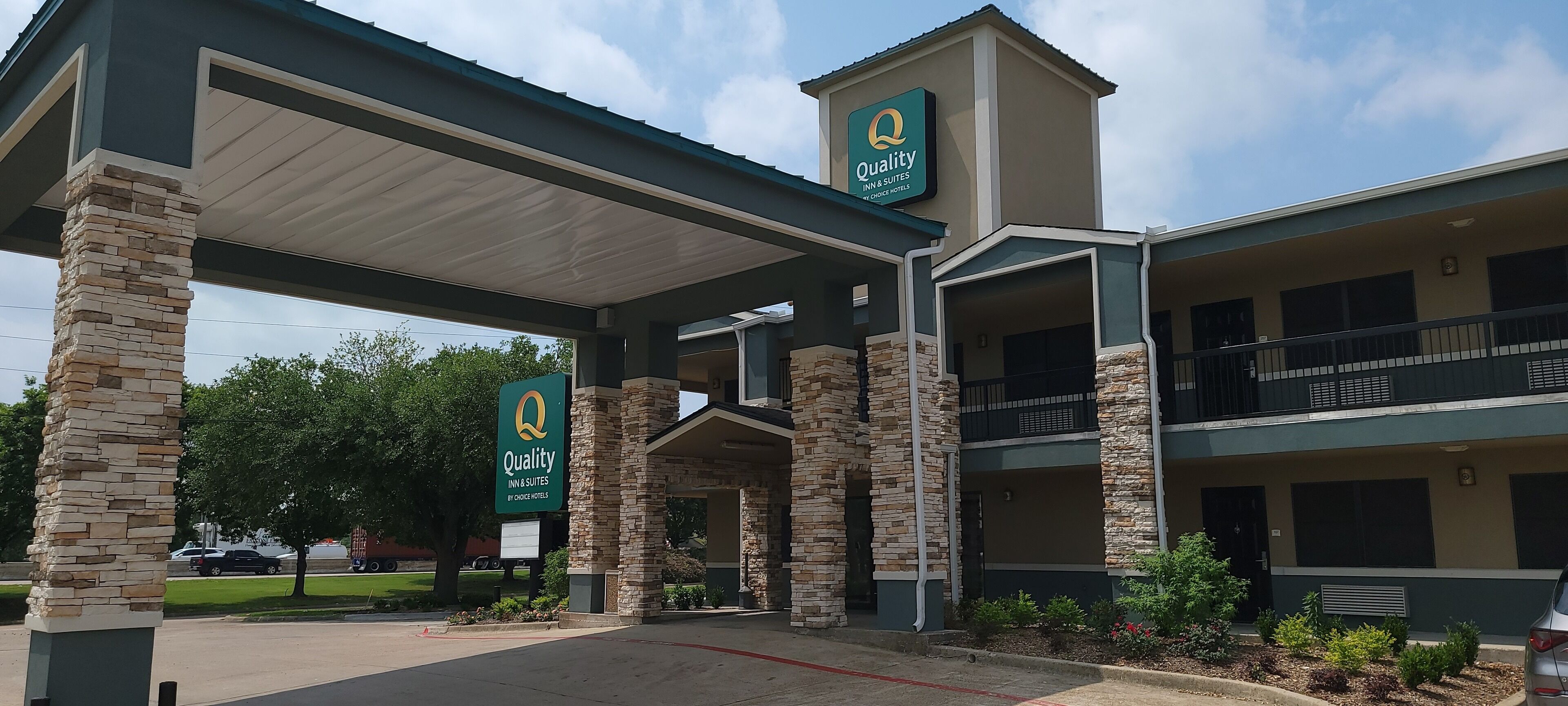 A hotel with a stone facade, multiple balconies, and a covered entrance.