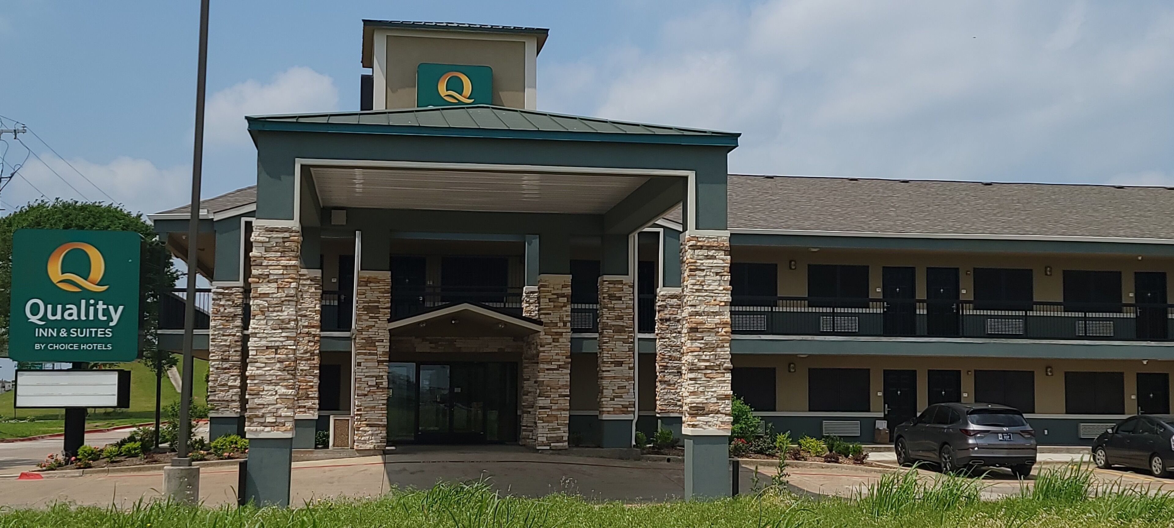 Un hôtel doté d’une façade en pierre, d’une entrée couverte et d’une enseigne indiquant qu’il fait partie de la chaîne Quality Inn & Suites de Choice Hotels.