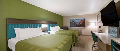 A hotel room with two beds, a desk, a chair, a TV, and a painting on the wall.
