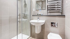 A modern bathroom with a glass shower enclosure, a white sink, and a toilet.
