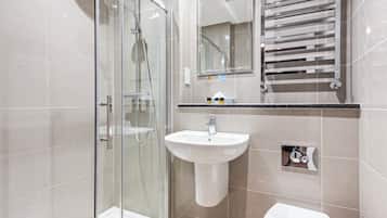 A modern bathroom with a glass shower enclosure, a white sink, and a toilet.