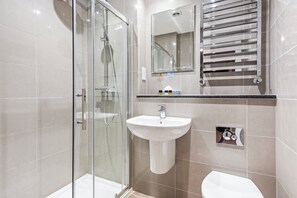 A modern bathroom with a glass shower enclosure, a white sink, and a toilet.
