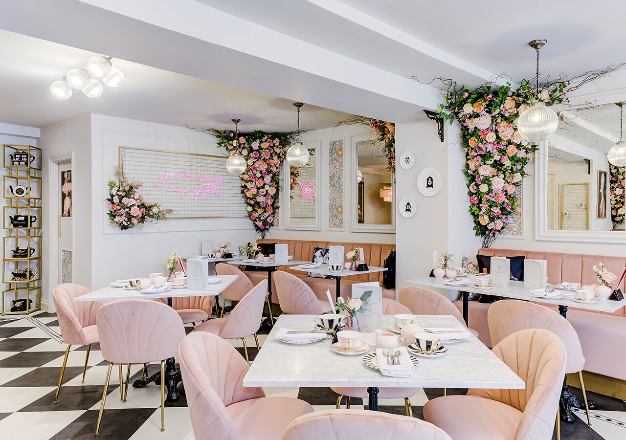 Un restaurant avec des chaises roses, des tables blanches et une décoration florale.