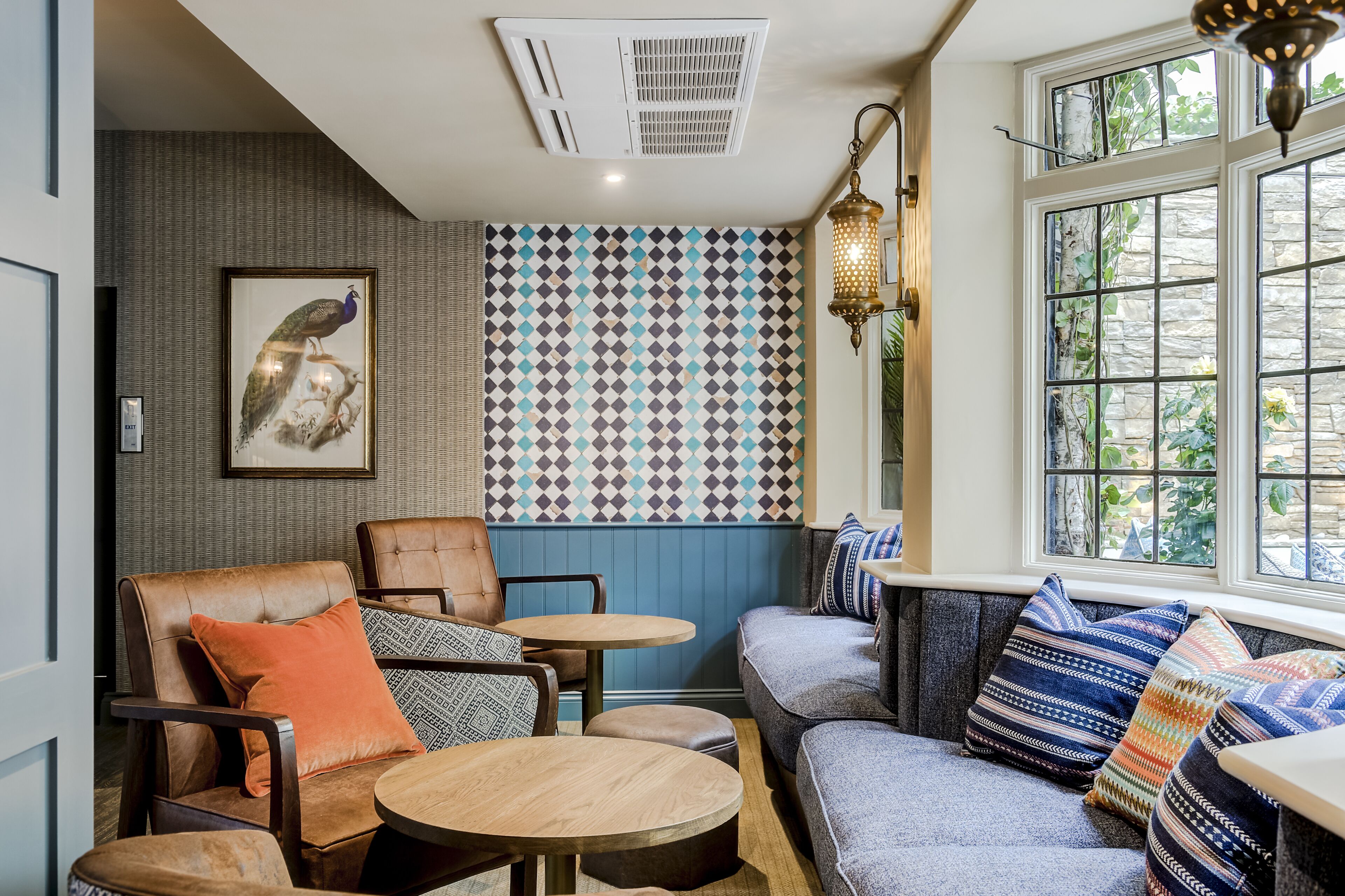 A cozy seating area with a patterned wall, a framed artwork, and a window with a view.