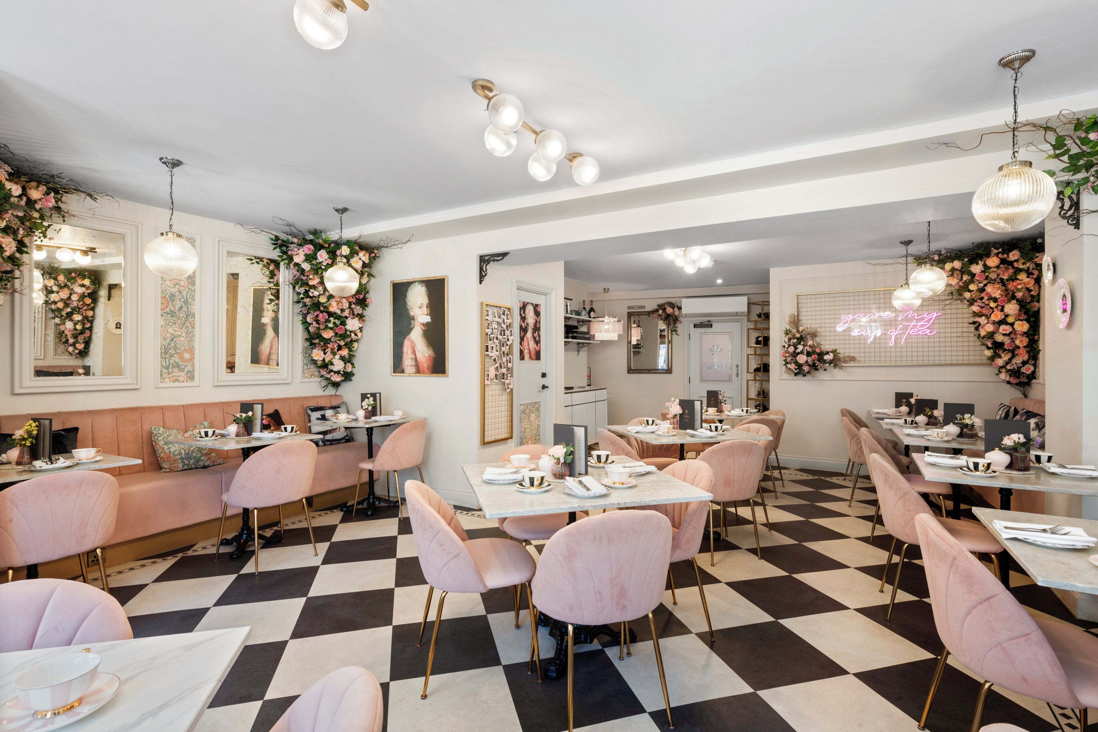 A restaurant with a checkered floor, pink chairs, and tables set for dining.
