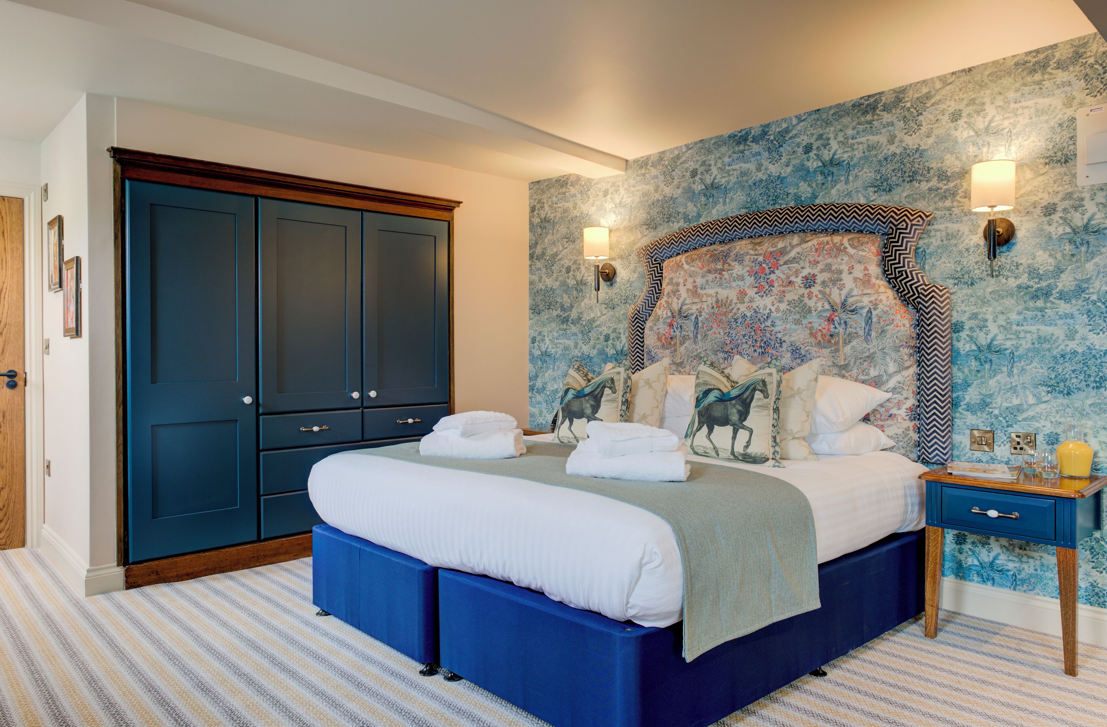 A bedroom with a large bed, a wardrobe, and a nightstand.