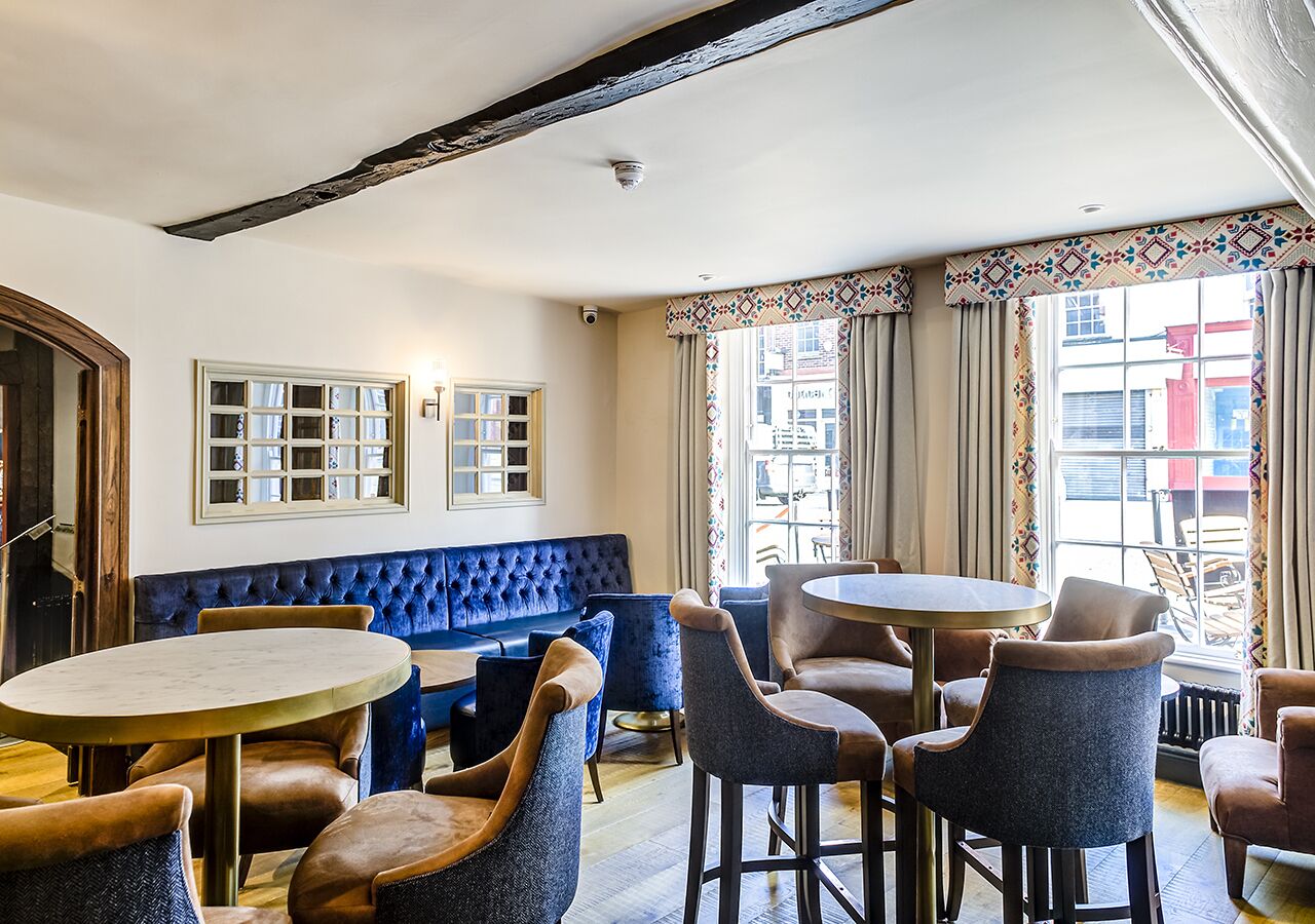 Een gezellig interieur met een blauwe gestoffeerde bank, ronde tafels en stoelen.
