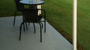 A patio with a table and chairs overlooking a lake. - Colonial Court Motor Inn (Kempsey)