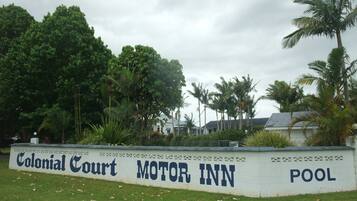 Naamplaatje voor Colonial Court Motor Inn met een zwembad.