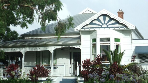 A two-story house with a prominent front porch, a decorative gable, and a visible chimney. - Colonial Court Motor Inn (Kempsey)