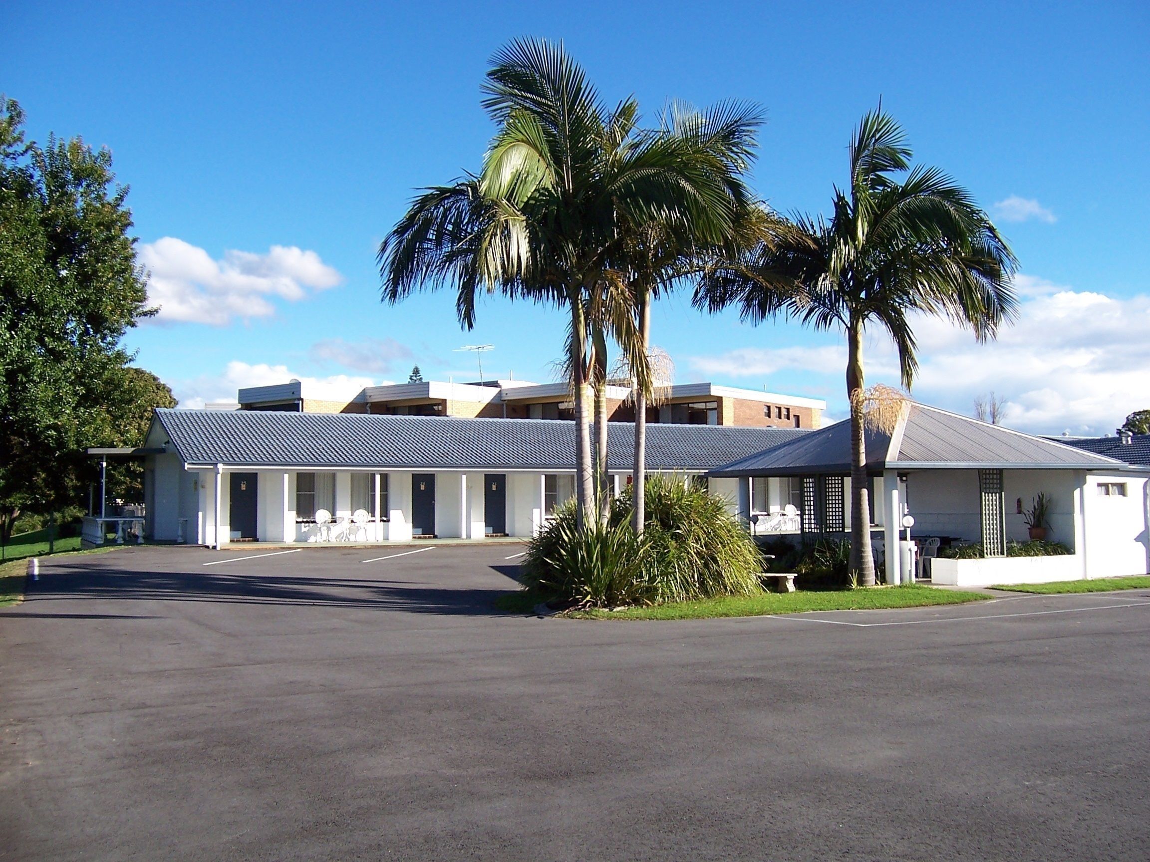 A motel with a central parking area, multiple rooms, and a covered outdoor seating area.