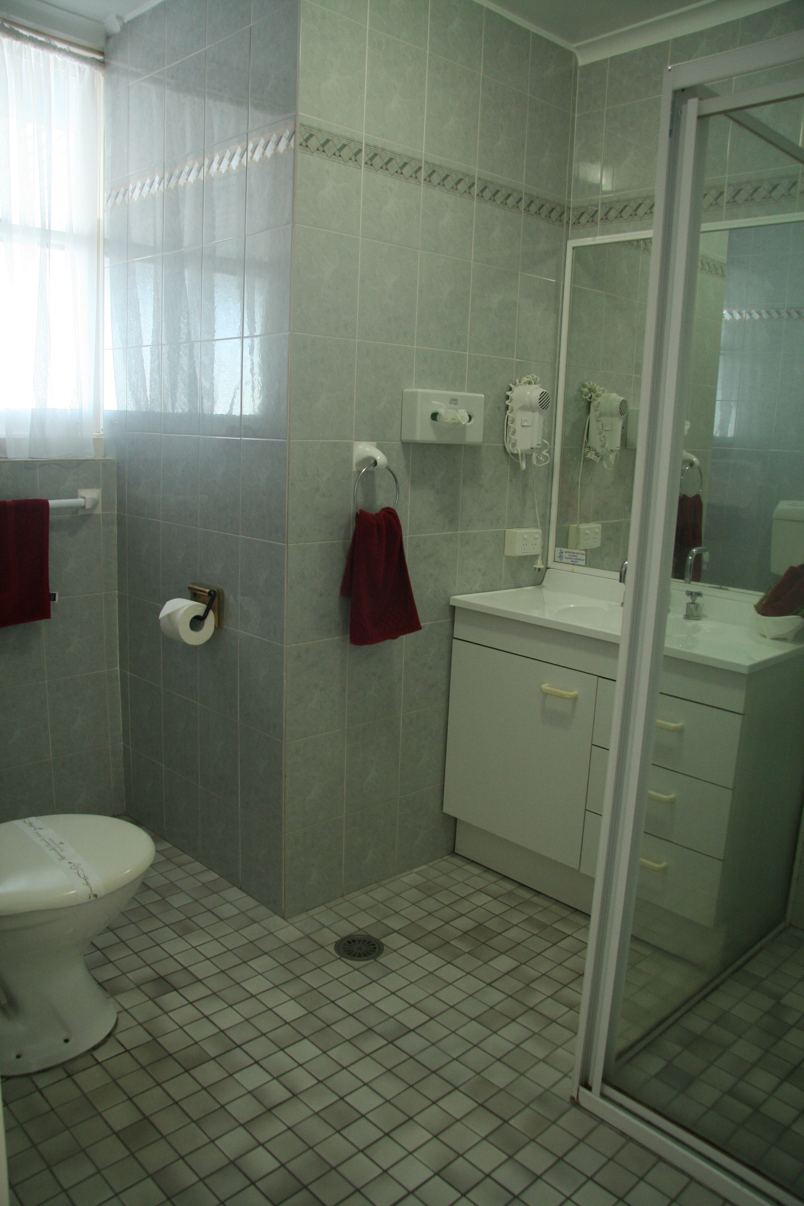 Une salle de bain avec des toilettes, un lavabo et une douche.