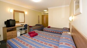 A hotel room with two beds, a desk with a television, a chair, and a mirror.