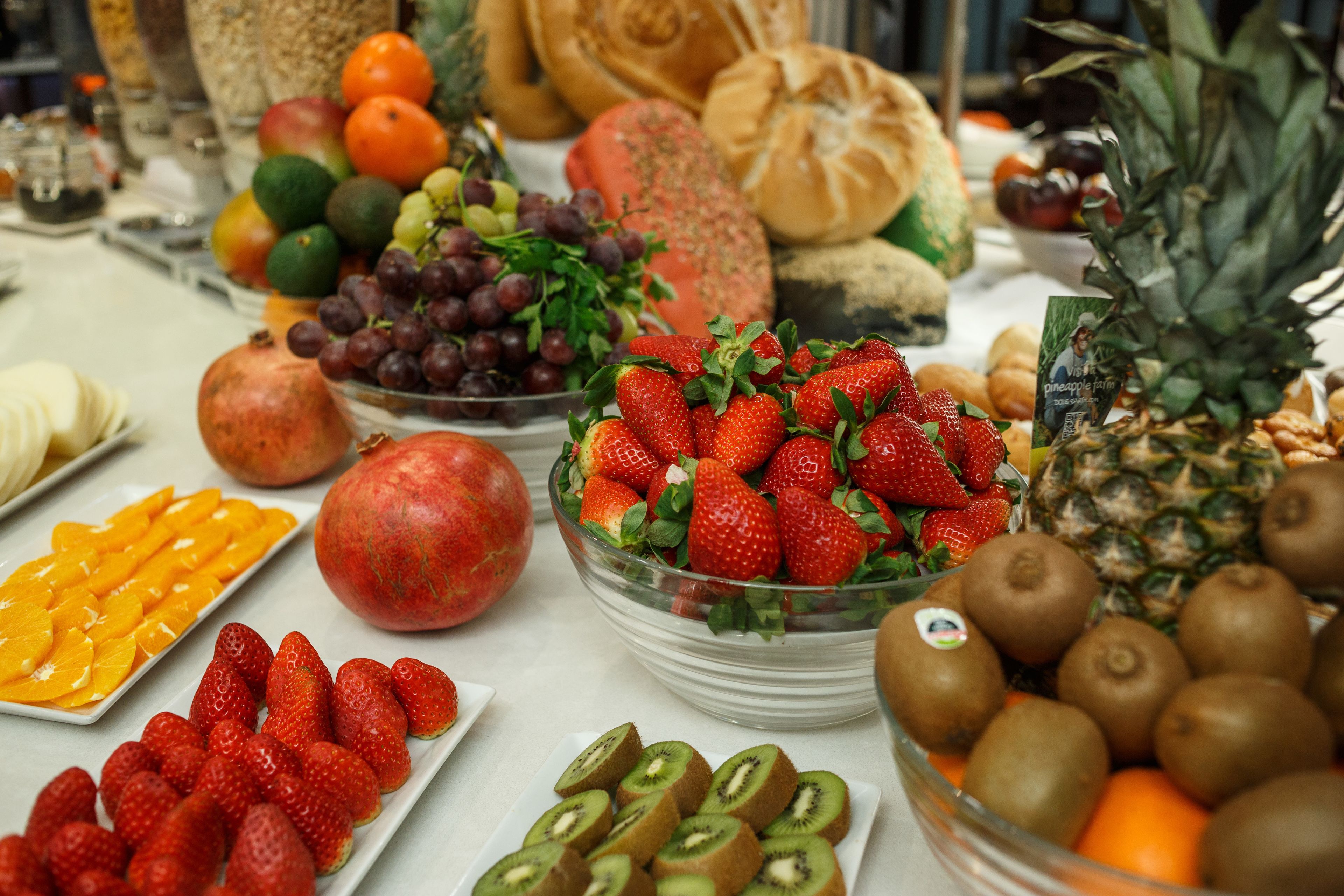 Una mesa con frutas y verduras diversas, entre ellas fresas, kiwi y piña.