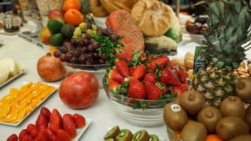 Una mesa con frutas y verduras diversas, entre ellas fresas, kiwi y piña.