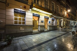 A szálloda homlokzata kőből készült, nagy ablakokkal és kültéri ülőhellyel rendelkezik.