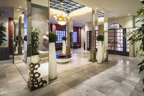 A spacious lobby with a high ceiling, a central seating area, and a chandelier. - Hotel Comfort Dauro 2 (Granada)