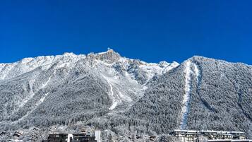 A mountain range with snow-covered slopes and a clear blue sky.