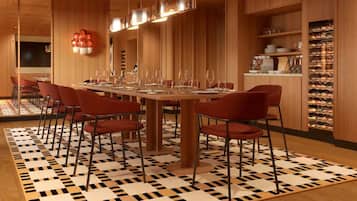 A dining area with a long table, red chairs, and a patterned floor.